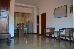 een woonkamer met stoelen en een tafel en een koelkast bij White House Apartment at Hume's Road in Galle