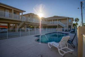a swimming pool with two chairs and a building at Charming Manasota Key duplex with beach access- IB14 in Englewood
