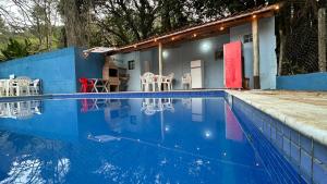 a house with a swimming pool with tables and chairs at Suites Oceano in Caraguatatuba