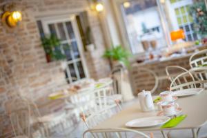 a white table and chairs in a restaurant at Logis Hôtel De Bretonnière - Beaune centre in Beaune