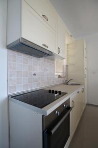 a kitchen with white cabinets and a black stove top oven at Apartments Marovic in Herceg-Novi