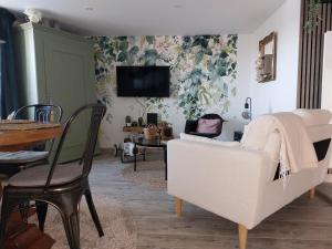 a living room with a white chair and a tv at La Petite Bohème, sauna in Lorquin