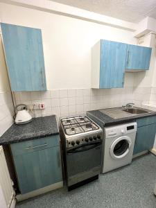 a kitchen with a stove and a sink and blue cabinets at Studio close to tower bridge in London