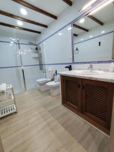 a bathroom with a sink and a toilet and a mirror at Casa Abuela Encarna in Hornachuelos