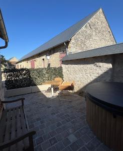 a patio with two benches and a stone wall at Le cottage Maisonnette dans corps de ferme in Allainville +22 photos
