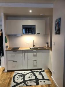 a kitchen with white cabinets and a sink and a rug at Le Bassin à vos pieds avec T2 Élégant entre Plage et Hyper Centre in Arcachon