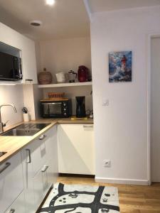 a kitchen with white cabinets and a microwave at Le Bassin à vos pieds avec T2 Élégant entre Plage et Hyper Centre in Arcachon