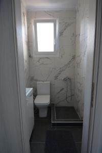 a bathroom with a toilet and a window at IRON House in Kavála