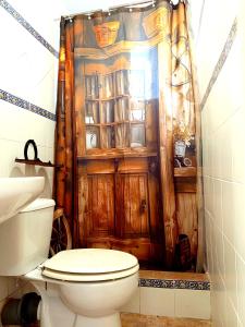 a bathroom with a toilet and a wooden shower curtain at El Girasol yellowstone in Chiclana de la Frontera