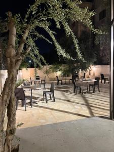 a group of tables and chairs next to a tree at Downtown Inn Madaba in Madaba