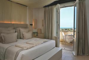 a bedroom with a large white bed and a balcony at Borgo Egnazia in Savelletri di Fasano