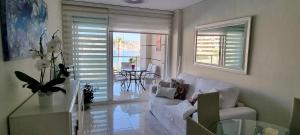 een woonkamer met een witte bank en een tafel bij Magic holiday - 1st line, seaview, pool & parking in Ifach