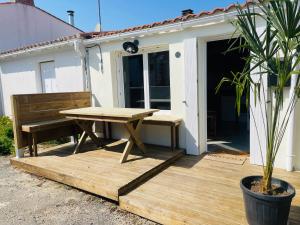 a picnic table and a bench on a wooden deck at Petite maison en bord de mer in Longeville-sur-Mer