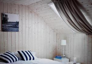 Schlafzimmer mit Holzwänden, einem Bett und einem Fenster in der Unterkunft Nordkappferie in Gjesvær