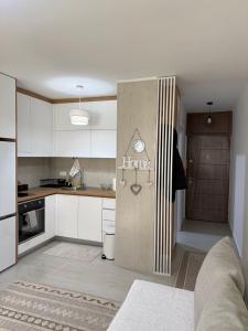 a kitchen with white cabinets and a door with the word evolve at Sanja apartman in Bar
