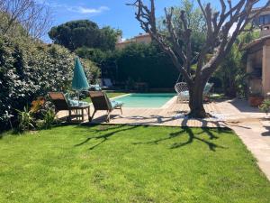 a yard with two chairs and a table and a pool at Villa golfe de St Tropez in Cogolin
