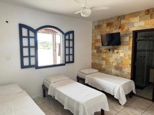 a room with two beds and a flat screen tv at Hotel Nossa Senhora da Conceição in Sabará