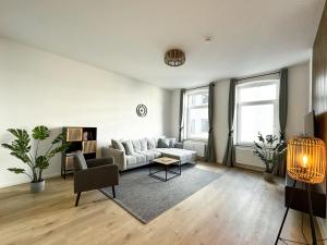 a living room with a white couch and a chair at Stobbe Stays I Zentral I Parkplatz I Kingsize I 116qm in Hannover