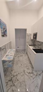 a white kitchen with marble floors and a sink at K&A Luxury Apartment in Anzio