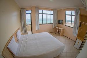 a bedroom with a large white bed and windows at Litorânea Praia Hotel in São Luís +21 photos
