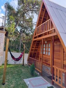 a log cabin with a hammock in the yard at Chalé Família Rigolo 1 Anthony in Monte Verde
