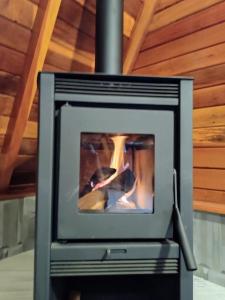 a wood stove in a room with a wooden ceiling at Chalé Família Rigolo 1 Anthony in Monte Verde