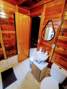 a bathroom with a sink and a toilet and a mirror at Chalé Família Rigolo 1 Anthony in Monte Verde