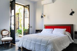 een slaapkamer met een bed met een rood hoofdeinde en een stoel bij Bellinzona Boutique in Buenos Aires