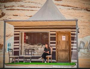 a woman sitting on a bench in a tiny house at Rum moon in Wadi Rum