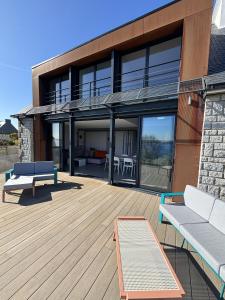a house with a deck with a couch and tables at Ty Ana Gwen in Trébeurden