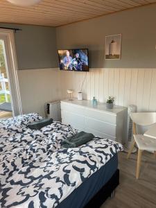 a bedroom with a bed and a tv on the wall at Bondehytten in Løkken