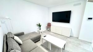 a white living room with a couch and a tv at The white house in Vecindario