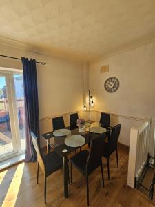 a dining room with a table and chairs and a clock at Spacious Bournemouth Home with BBQ, Outdoor Seating & large TV in Bournemouth +8 photos