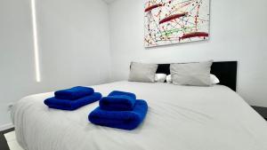 a white bed with blue pillows on top of it at The white house in Vecindario