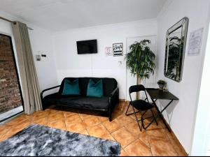 a living room with a black couch and a table at Zhantique Guest House 1- Unit 5 in Boksburg