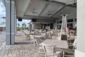 Un restaurante con mesas y sillas blancas en un patio. en Chic and elegant waterfront home in Lorraine Lakes - Patsgang, en Bradenton