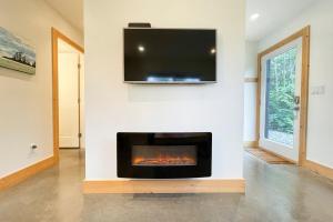 a living room with a fireplace and a flat screen tv at Tidal Retreat Cabin in Tofino +19 photos