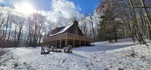 a house in the snow in a snow covered forest at Wandering Woods- 3 Bedroom Home with Hot Tub and Firepit in Oakland