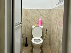 a bathroom with a toilet with a pink bottle on it at Pelangi Highway Homestay Kuning,A4 in Bukit Gambir +1 photo