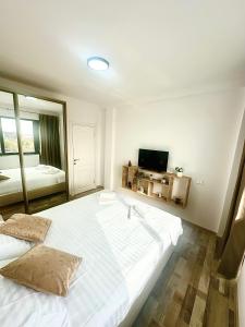 a large white bed in a room with a television at North Boutique Apartments in Mamaia Sat/Năvodari