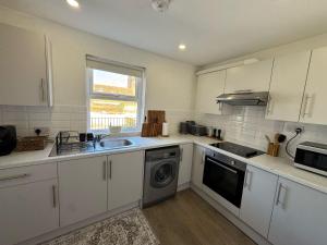 a kitchen with white cabinets and a sink and a dishwasher at Rustic Elegance Town Centre Flat in Ipswich