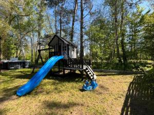 un parco giochi con scivolo blu nell'erba di Bungalow in Dziwnów near Baltic Sea a Dziwnów