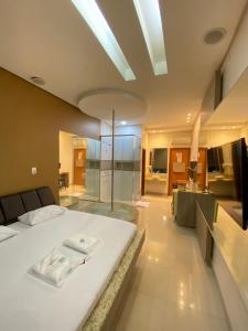 a bedroom with a large white bed and a bathroom at Rodotel Venus (Adults Only) in Jataí