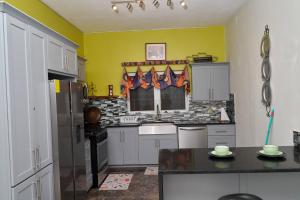 a kitchen with white cabinets and yellow walls at Bondi's Getaway in Portmore +3 photos