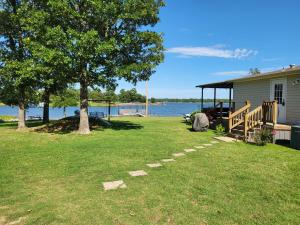 a house with a tree in the grass near the water at Cute Shawnee Twin Lakes home sleeps 10&has it all! in Shawnee