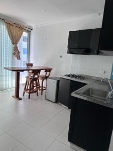 a kitchen with a sink and a table with a table at Hotel Rodadero Suites By SGH in Santa Marta