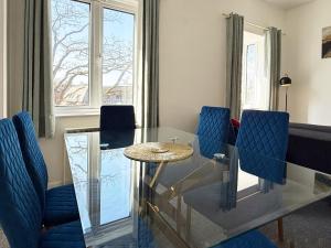 a dining room with a glass table and blue chairs at Fiona Place in Winchester city center- 3 Double Beds, 2 Single Beds, 2 Sofa Beds - FREE parking available upon request in Winchester