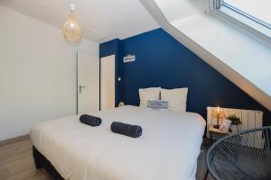 a bedroom with a white bed with a blue wall at La Marine, maison en plein cœur de Wimereux in Wimereux