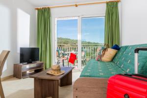 a living room with a couch and a television and a balcony at Apartaments Condado by Marsol in Lloret de Mar