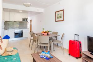 a kitchen and dining room with a table and a red suitcase at Apartaments Condado by Marsol in Lloret de Mar